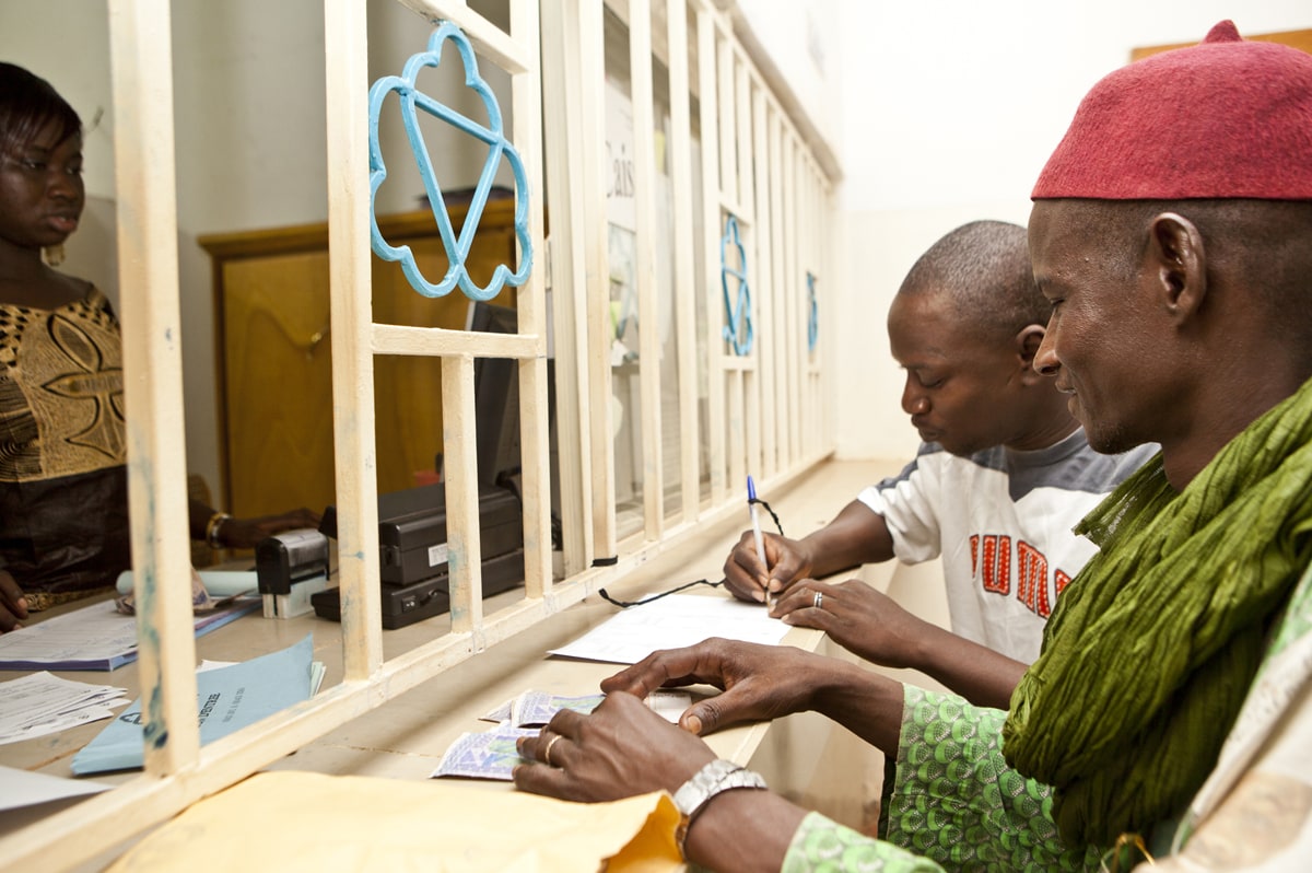 Deux clients remplissant un formulaire au guichet d'une institution de microfinance